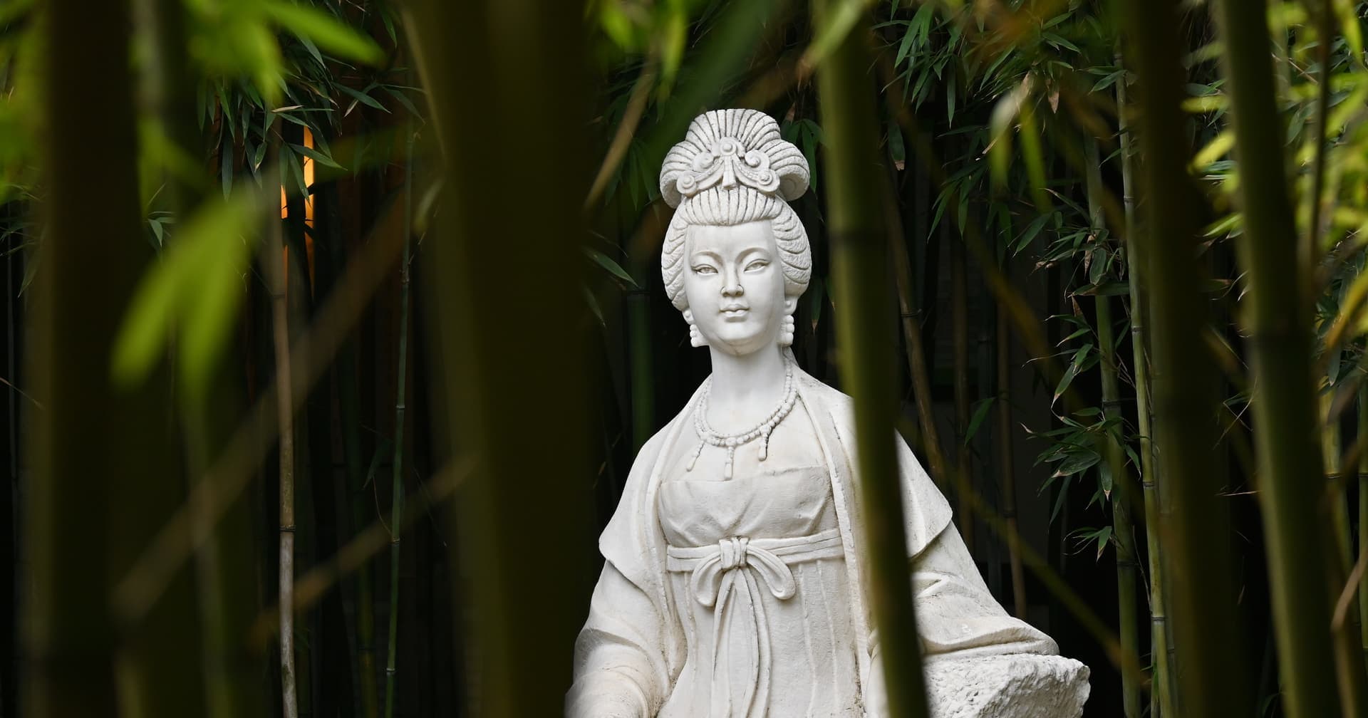 A classical stone statue of a woman in a bamboo grove — testing the reading against the chart of a historical figure