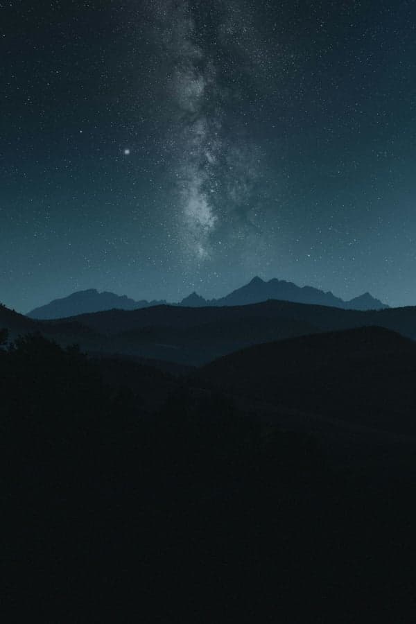 The Milky Way arching over a mountain ridge — the breadth of relationships read through the Cosmic Board
